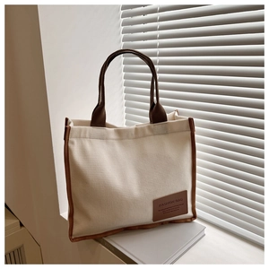 Close-up of waffle texture canvas tote bag with brown leather tag and strap details