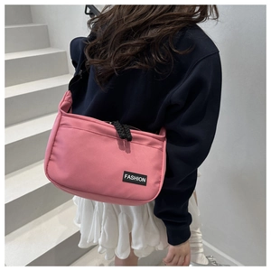 Pink nylon crossbody bag with fashion tag worn by a model in a minimalist setting