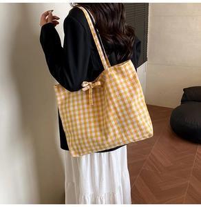 Detail of yellow and white gingham tote bag with side bow tie and soft fabric texture
