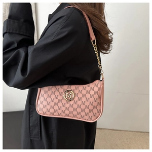 Detail of pink hobo bag featuring repetitive M patterns and gold metallic chain strap