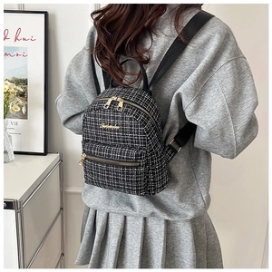 Vue détaillée du mini sac à dos en tweed noir et blanc avec fermeture éclair dorée chic