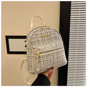 Détail d'un petit sac à dos en tweed noir et blanc avec fermeture éclair dorée