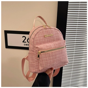 Gros plan du mini sac à dos en tweed rose avec logo en métal doré et détails de texture