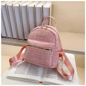 Détail du sac à dos en tweed rose avec zip doré posé sur un livre élégant en arrière-plan