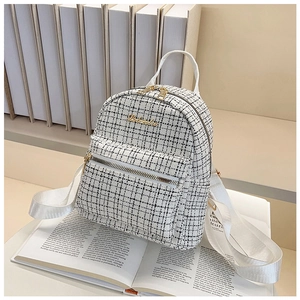 Gros plan détaillé d'un sac à dos en tweed noir et blanc avec logo doré sur un livre
