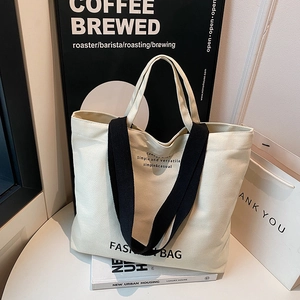 Minimalist canvas tote bag with black straps and fashion print in a modern setting