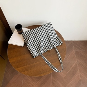 Classic black and white gingham tote bag with tie-up bow on a wooden table with coffee