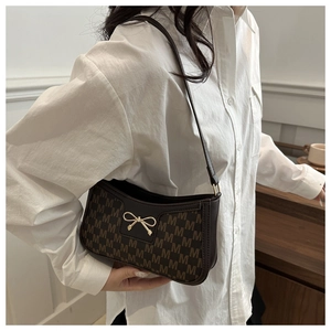 Detail of dark brown crescent bag with M-pattern canvas and golden bow buckle
