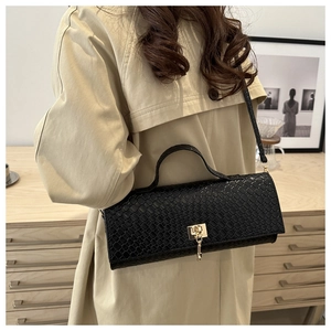 Gros plan du sac en similicuir gaufré noir avec boucle dorée et bandoulière chic