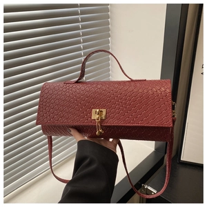 Close-up of wine red woven leather texture and gold buckle on a stylish square handbag