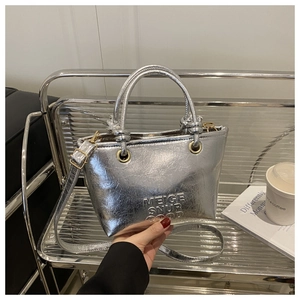 Dettaglio della borsa a secchiello argento con texture increspata e finiture dorate