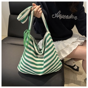 Détail d'un sac cabas en toile rayé vert et blanc avec un ruban de dentelle décoratif