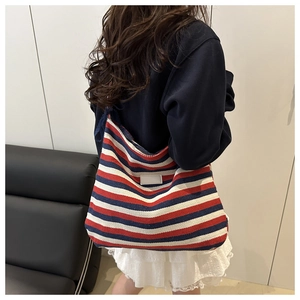 Détail du sac cabas en toile à rayures rouges, blanches et bleues avec logo en cuir