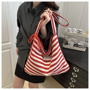 Détail d'un sac cabas en toile à rayures rouges et blanches avec nœud en dentelle