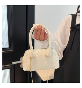 Detail of white litchi pattern leather shell bag with golden chain and soft texture