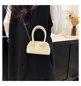 Detailed close-up of a stylish mini off-white shell bag with lychee grain texture