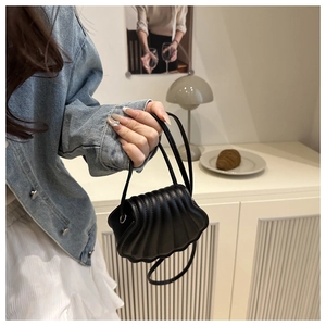 Close-up of black shell-shaped mini bag with textured stitching and wave-edge design