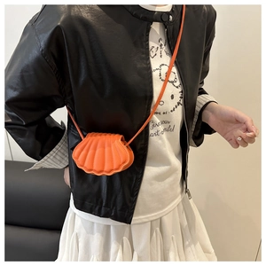 Detail of a vibrant orange shell-shaped mini crossbody bag with vertical quilting textures