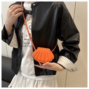 Detail of a bright orange shell-shaped mini crossbody bag with textured faux leather