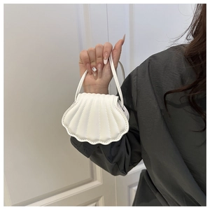 Close-up of white shell-shaped mini handbag with embossed texture and wavy edges