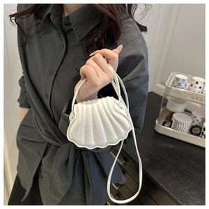 Detail shot of the white shell-shaped shoulder bag featuring elegant pleated texture