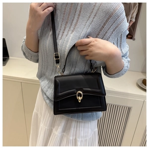 Detail of elegant black leather handbag with a golden oval metal clasp and top handle
