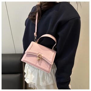 Pink faux leather crossbody bag with golden buckle shown on a model in daily outfit