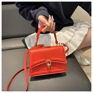 Detail of red crossbody bag featuring gold twist lock and parallel stitched texture