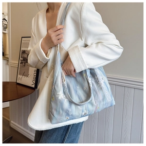 Close-up of light blue floral embroidery and lace detail on a large canvas hobo bag