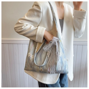 Close-up of light blue patterned handbag with lace bow and floral embroidery details