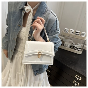 Detail of white leather flap handbag with gold interlocking hardware and top handle