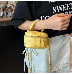 Detailed view of yellow quilted mini box bag with gold chain strap and metal zippers