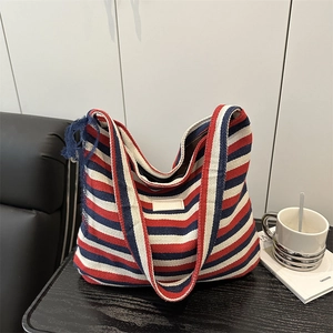 Sac cabas en tricot à rayures rouges, blanches et bleues avec bandoulière sur table bois