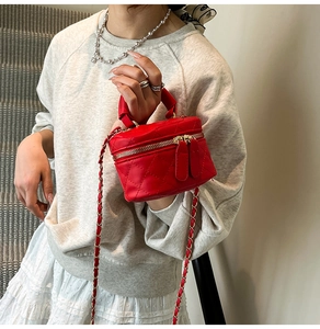 Detail of red quilted mini bag with gold chain strap worn as a stylish crossbody accessory