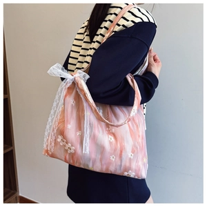 Floral embroidery shoulder bag with side lace bow detail shown on a model's shoulder