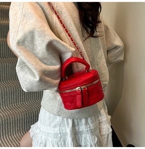 Detail of red quilted square handbag with chain strap shown on model's shoulder