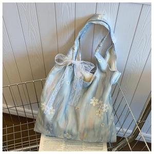 Detail of light blue floral tote with 3D white flower accents and lace bow decoration