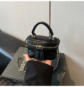 Macro detail of black quilted leather vanity bag with gold chain and handle