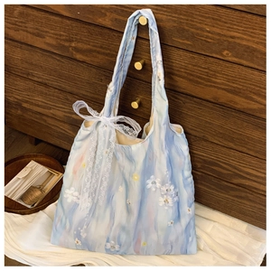 Detail of light blue floral tote bag with lace bow and 3D petal decorations