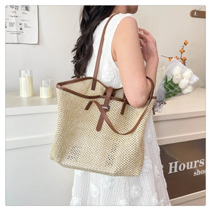 Detail of woven straw tote bag featuring brown leather trim and hollow-out mesh pattern
