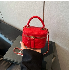 Detail of red quilted mini box bag featuring gold chain strap and dual zippers