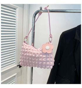 Detail of pink bubble texture fabric on crossbody bag with floral charm and knotted strap