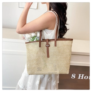 Chic woven straw tote bag with brown leather handles worn by a model in white lace dress