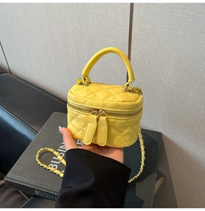 Close-up of bright yellow quilted box bag showing leather handle and dual metal zippers