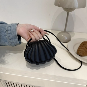 Minimalist black shell-shaped crossbody bag with quilted pattern in a soft lifestyle setting