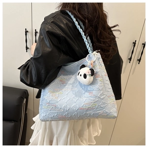Light blue quilted tote bag with colorful wave embroidery and a cute panda keychain