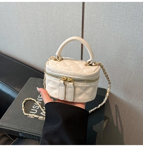 Detail of white quilted mini cylinder bag with gold chain strap and dual zippers