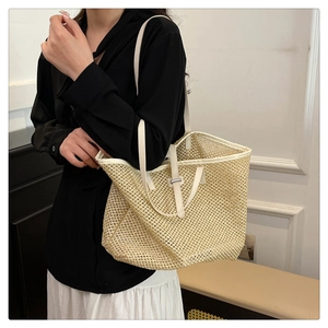 Close-up of beige woven tote bag with white leather straps and intricate mesh texture
