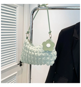 Detail of mint green ruched bag with bubble texture and floral charm on a hanger