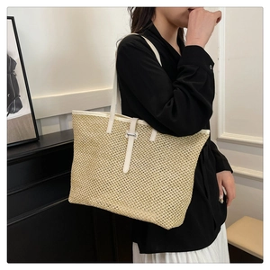 Detail of woven straw tote bag with white faux leather shoulder straps for vacation